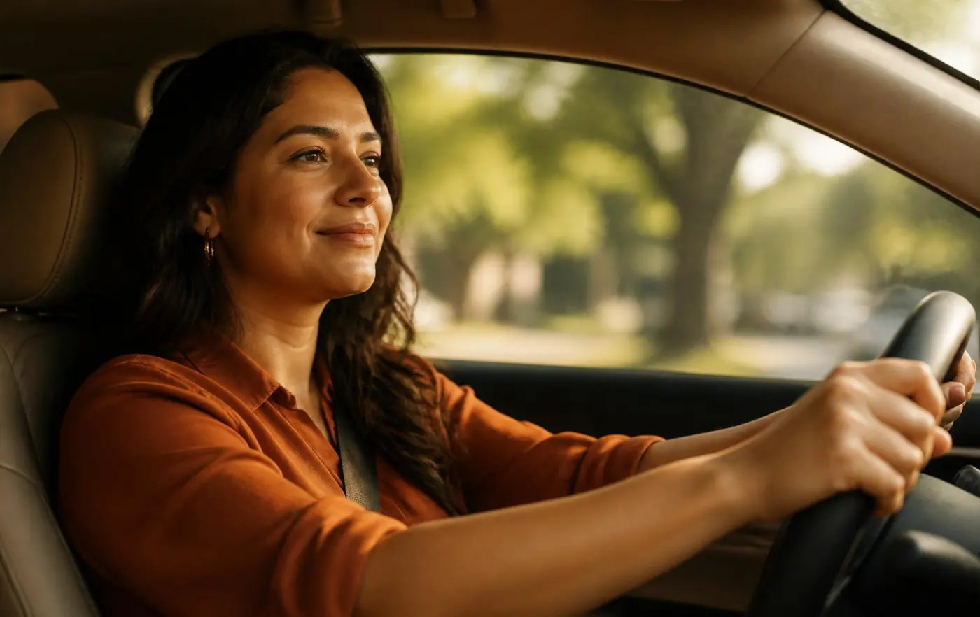 Mulher tranquila ao volante de um carro, com as duas mãos no volante e expressão serena, representando a superação do medo de dirigir